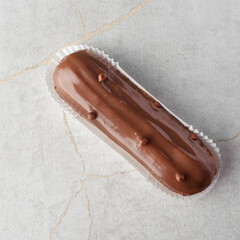 Traditional french dessert. eclair with custard and chocolate icing on a stone background. Pastry products for sweet tooth