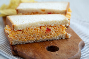 Homemade Pimento Cheese Sandwich with Chips on a rustic wooden board, side view. Close-up.