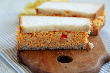 Homemade Pimento Cheese Sandwich with Chips on a rustic wooden board, low angle view. Close-up.