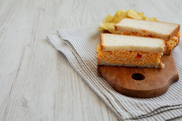Homemade Pimento Cheese Sandwich with Chips on a rustic wooden board, side view. Copy space.