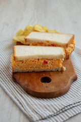 Homemade Pimento Cheese Sandwich with Chips on a rustic wooden board, side view.