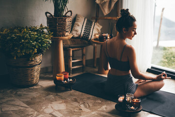 Young woman doing yoga in a cozy boho room.