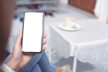 Cell phone mockup image blank white screen.  Woman hand holding, using mobile phone at home.