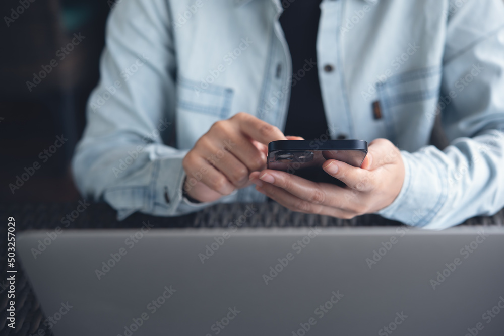 Poster casual business man using mobile smart phone and working on laptop computer on table at coffee shop
