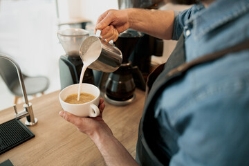 Fototapeta na wymiar Close up of Professional barista is making fresh takeaway latte from coffee machine