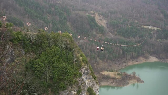 Two unrecognizable people launching on a zip line over the Bubal reservoir in the Tena valley, Huesca, Spain