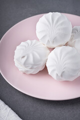 White marshmallows on a pink plate on a grey table
