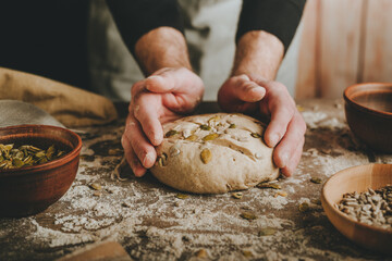 Young man making whole wheat bread with sunflower and pumpkin seeds