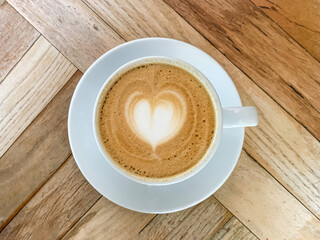 A cup of coffee latte On a wooden table. A mug of flat white coffee on a wooden background. Coffee art. Heart flower shape latte art. Copy space