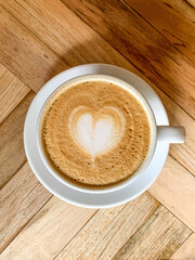 A cup of coffee latte On a wooden table. A mug of flat white coffee on a wooden background. Coffee art. Heart flower shape latte art. Copy space