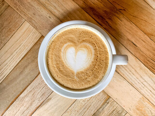 A cup of coffee latte On a wooden table. A mug of flat white coffee on a wooden background. Coffee art. Heart flower shape latte art. Copy space