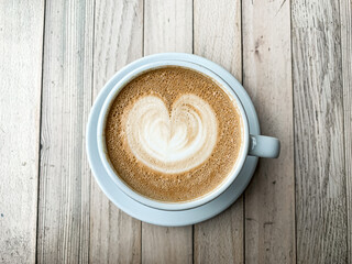 A cup of coffee latte On a wooden table. A mug of flat white coffee on a wooden background. Coffee art. Heart flower shape latte art. Copy space