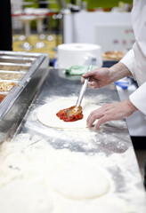 chef elaborando pizza con su ingrediente de tomate