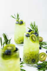 Refreshing drink with kiwi smoothie, summer sweet fruit juice with blueberries and rosemary