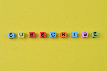 Colorful alphabet beads with text SUBSCRIBE isolated on a yellow background