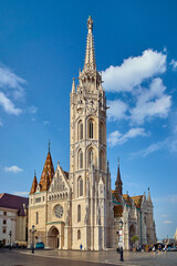 Fototapeta na wymiar Matthias Church in Budapest, outdoor view of the temple with clouds and blue sky
