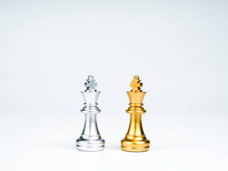 A golden king chess piece and a silver king chess piece are standing together isolated on white...