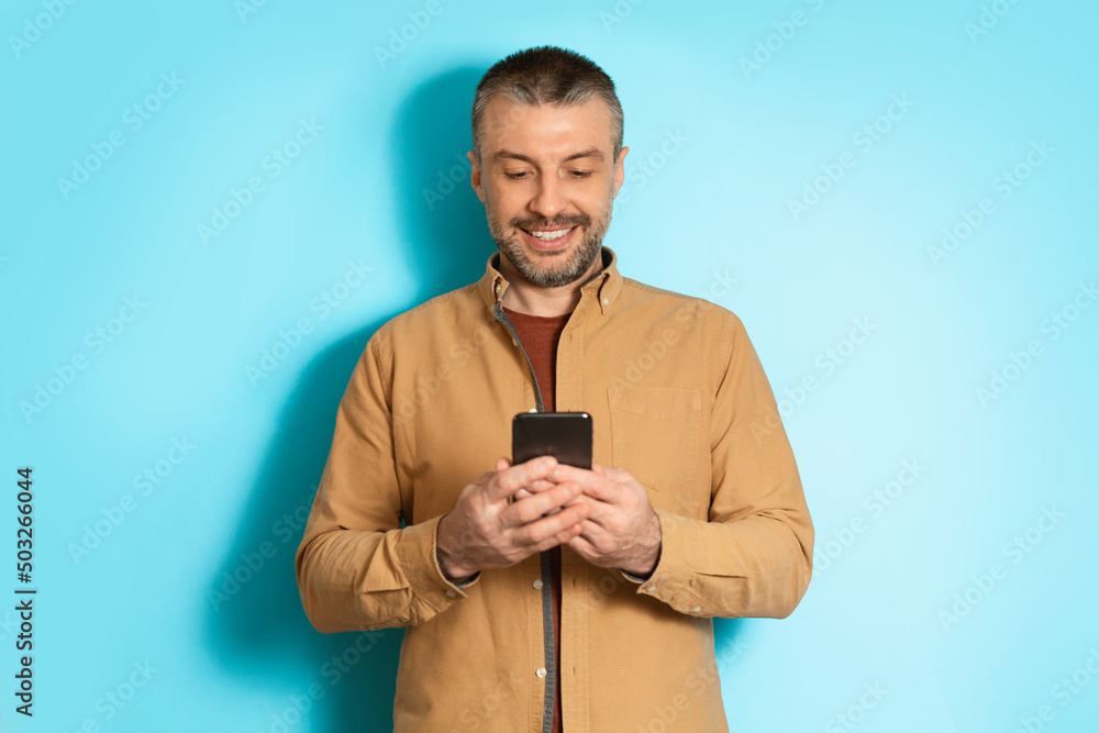 Poster Cheerful Man Using Mobile Application On Cellphone Over Blue Background