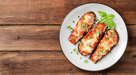 Baked eggplant with mozzarella cheese, chopped tomatoes and fresh basil leaves. Vegetarian food recipe. Wooden background. top view	