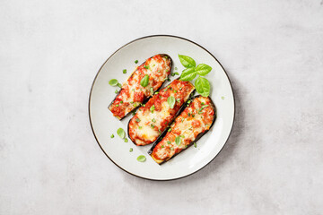 Obraz na płótnie Canvas Baked eggplant with mozzarella cheese, chopped tomatoes and fresh basil leaves. Vegetarian food recipe. Light gray background. top view