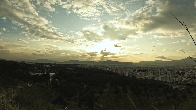 Time lapse video from a local cliff  shows a part of Athens with clouds passing by during sunset time.