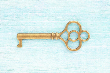 Bronze vintage antique key on blue wooden background. Concept of antiques