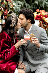 Young beautiful couple are kissing on the bar counter holding cocktails.