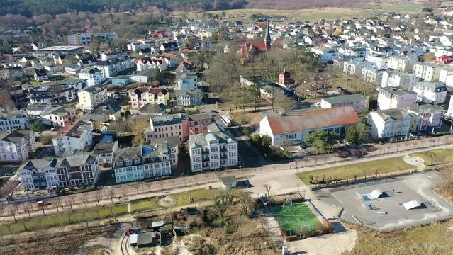 Aerial top view - panning right with beach prommenad coastline and Pier around city of Ahlbeck on the peninsula Usedom in Germany during a sunny day in early spring. Pier juts out into the Baltic Sea.