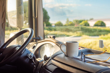 Cup of coffee and reading glasses on the dashboard of a stopped truck taking the regulatory break.