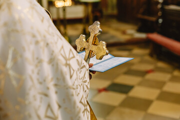 The priest holds a cross on the background of the floor in the church