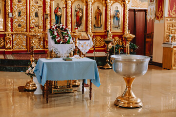 Fototapeta na wymiar Bowl and table with items for the baptism of a child near the altar in the church
