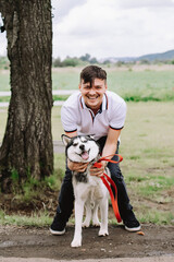 Naklejka na ściany i meble Man playing with husky dog on nature background in park