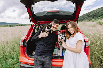 Family with a cat and a dog in nature on the background of his car