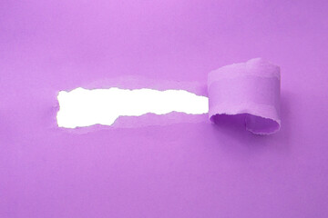 Hole in paper violet color background damaged ripped