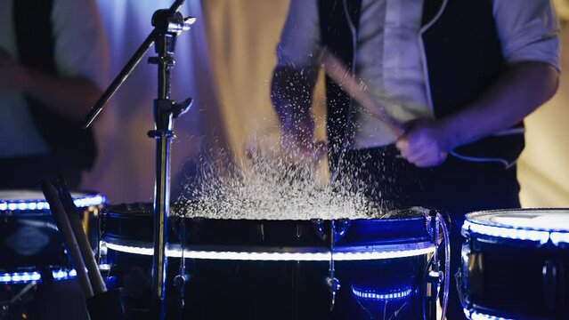 Splashes of water fly from the surface of the drums when hitting them. Shooting at a drum show