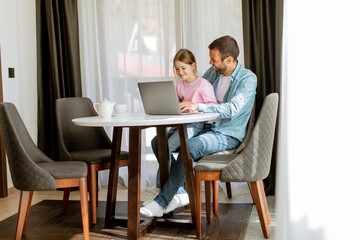 Father and daughter using laptop computer together