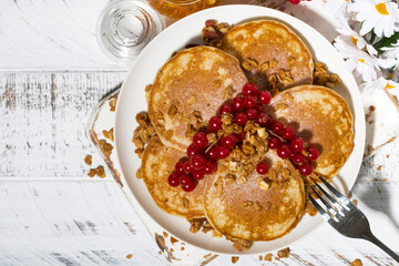 tasty pancakes with berries and honey on a white wooden table, top view