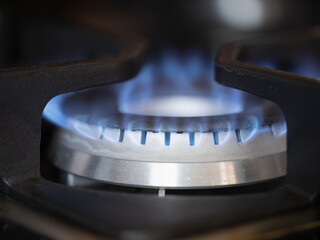 Gas burner on stove with blue fire at home closeup