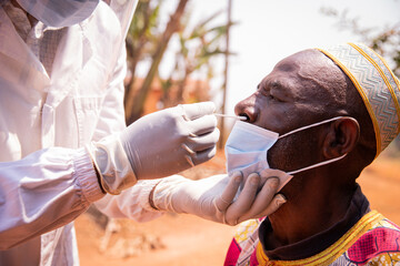 African senior man is tested for coronavirus with a swab inserted into his nose, healthcare and medicine in africa.