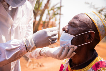 African senior man is tested for coronavirus with a swab inserted into his nose, healthcare and...