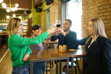 Diverse friends clinking glasses over table in beautiful pub