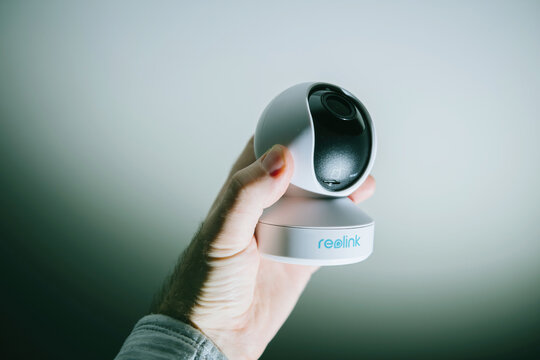 Paris, France - Jan 31, 2022: POV Male Hand Holding New Small Reolink 5MP PTZ Cctv Surveillance Camera - White Gray Background