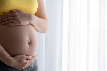 Woman touching with hands her naked pregnant belly. Baby expectation, care and wellness on pregnancy time.