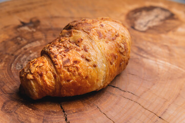 Close-up of a delicious croissant with almonds on a wooden pallet. Delicious and healthy breakfast