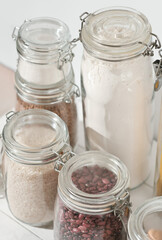 uncooked food storage. glass eco jars, flour and beans, rice and sugar. kitchen pantry vertical shot