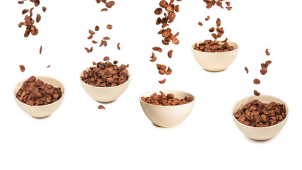 Chocolate corn flakes falling to the white bowl isolated on white. Motion.
