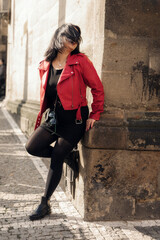 A pretty young woman stands next to wall and the wind covered her face with hair