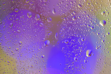 Purple bokeh behind wet glass