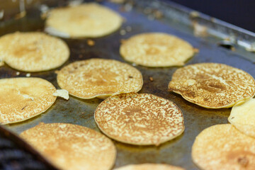 The cook is frying a large number of pancakes