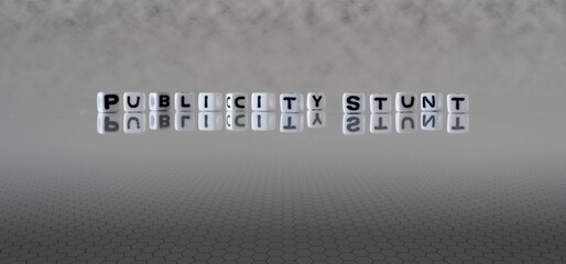 publicity stunt word or concept represented by black and white letter cubes on a grey horizon...